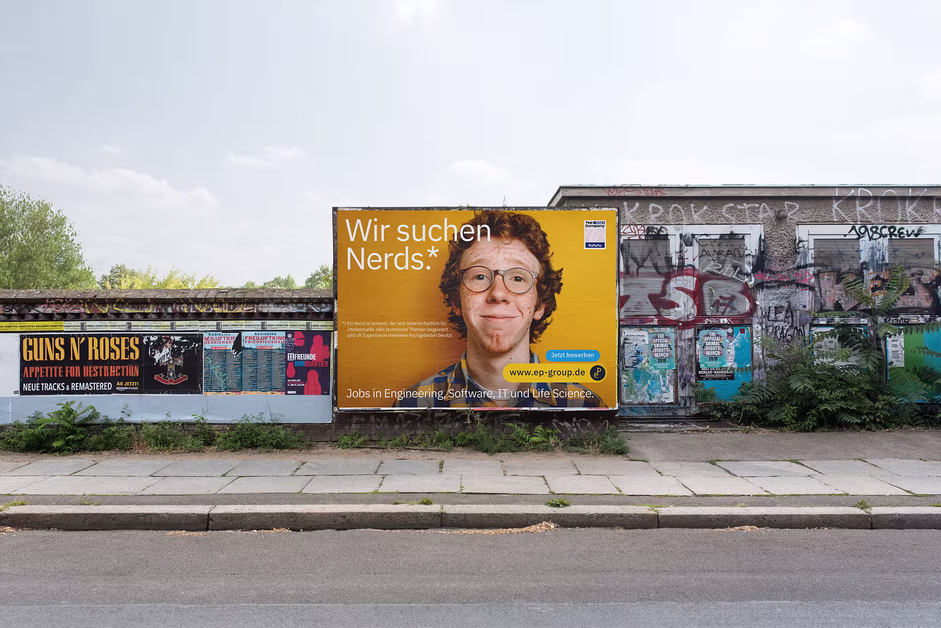 Plakat mit gelbem Hintergrund und Headline „Wir suchen Nerds.*“, im Mittelpunkt ein junger Mann mit Brille und lockigem Haar.