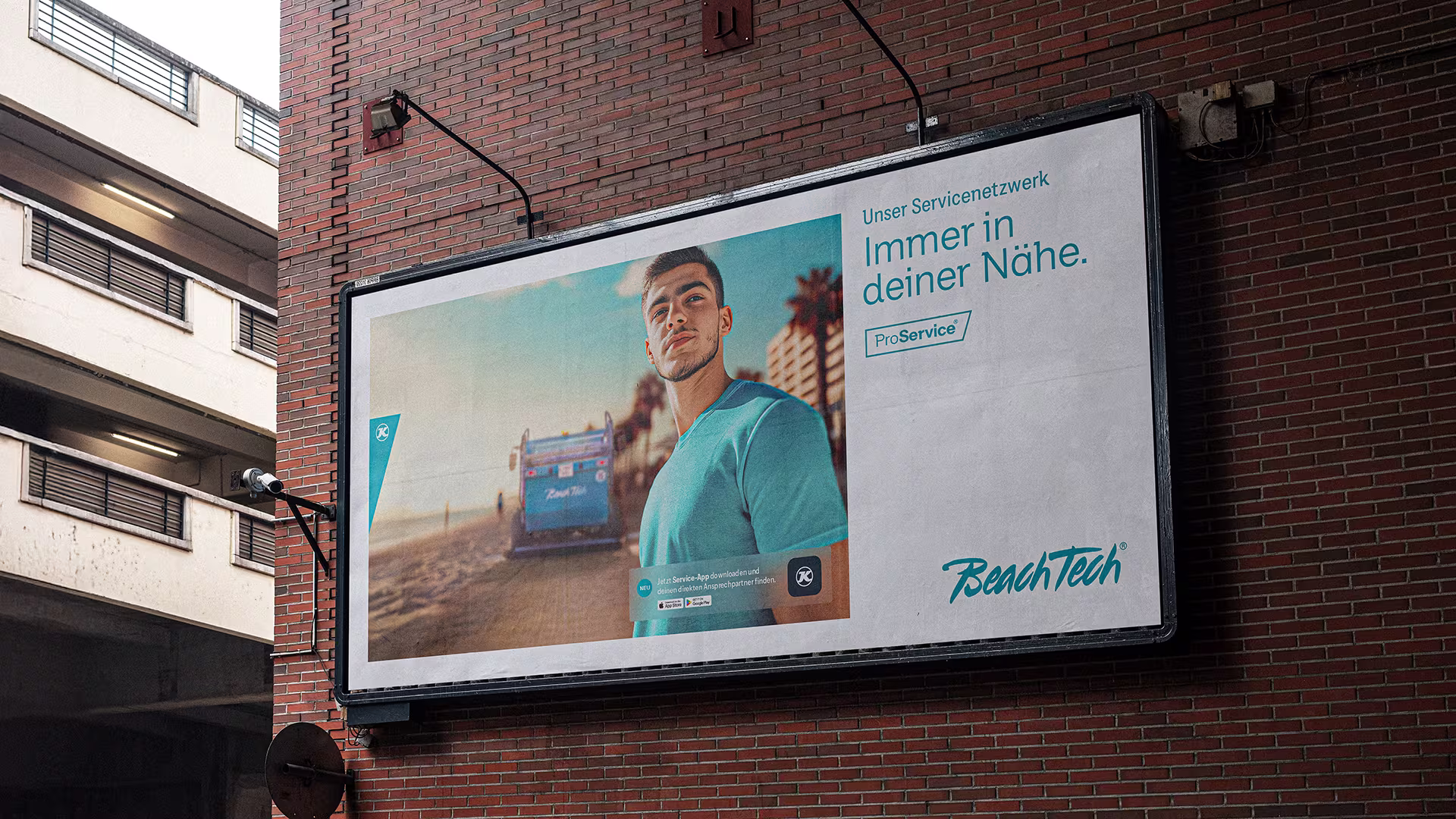 BeachTech-Werbeplakat an Ziegelwand mit Mann im Vordergrund und Strandreiniger im Hintergrund, Text: „Immer in deiner Nähe“.